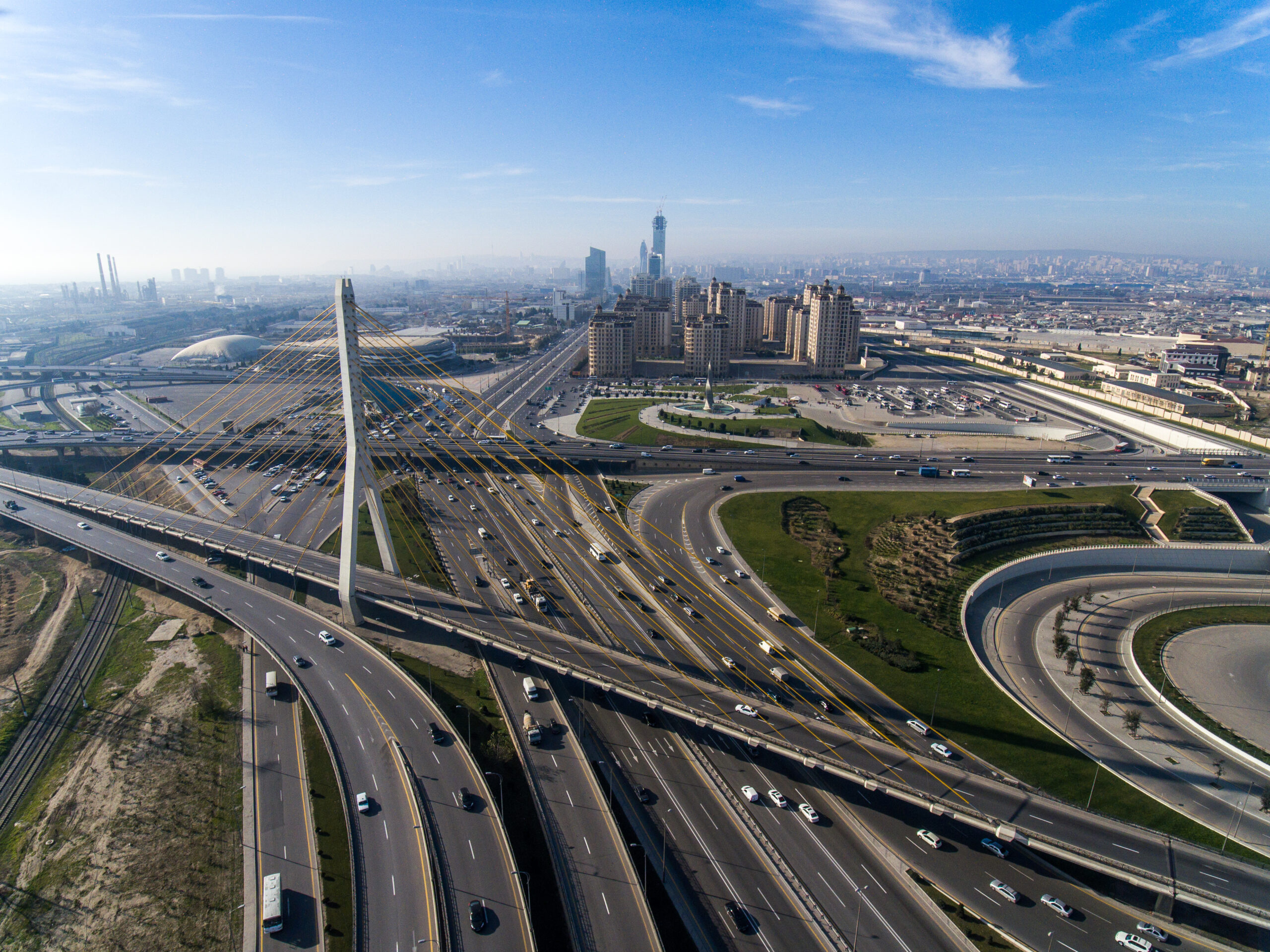 Aerial view of highway interchange with cable-stayed bridge and city skyline in background