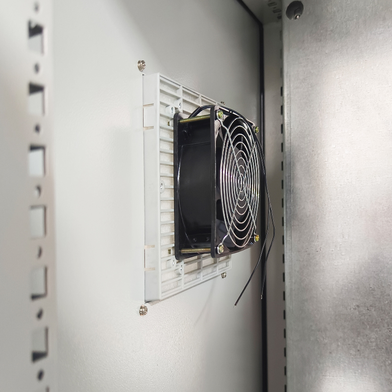 Cooling fan mounted on vent grille inside gray metal electrical equipment cabinet