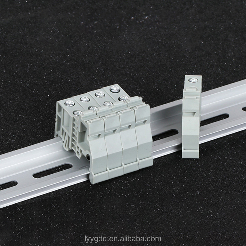Close-up of gray DIN rail terminal block with end stop on industrial mounting rail.