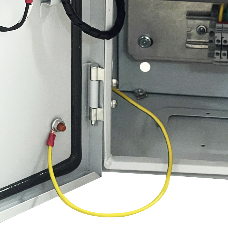 Yellow grounding bond wire linking electrical cabinet door to enclosure