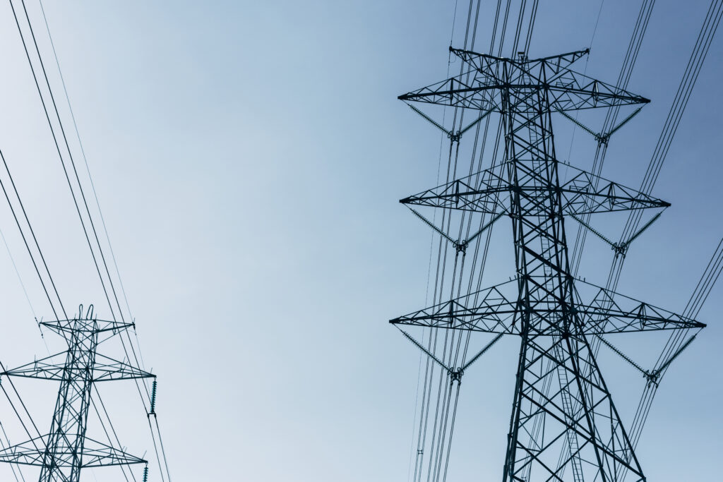 High-voltage transmission towers with power lines stretching across a clear blue sky