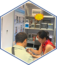 Customer receiving smartphone assistance at electronics kiosk service counter indoors.
