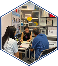 Three coworkers collaborate at a small office table reviewing documents in a workspace.