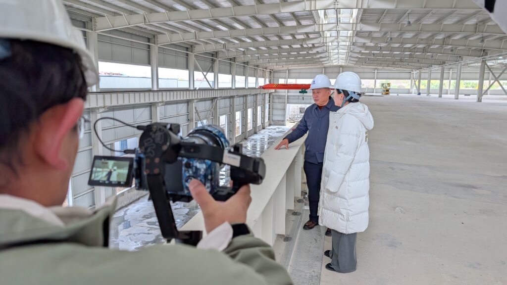 Video crew filming Keystone Metalcraft facility tour inside large industrial barn structure.